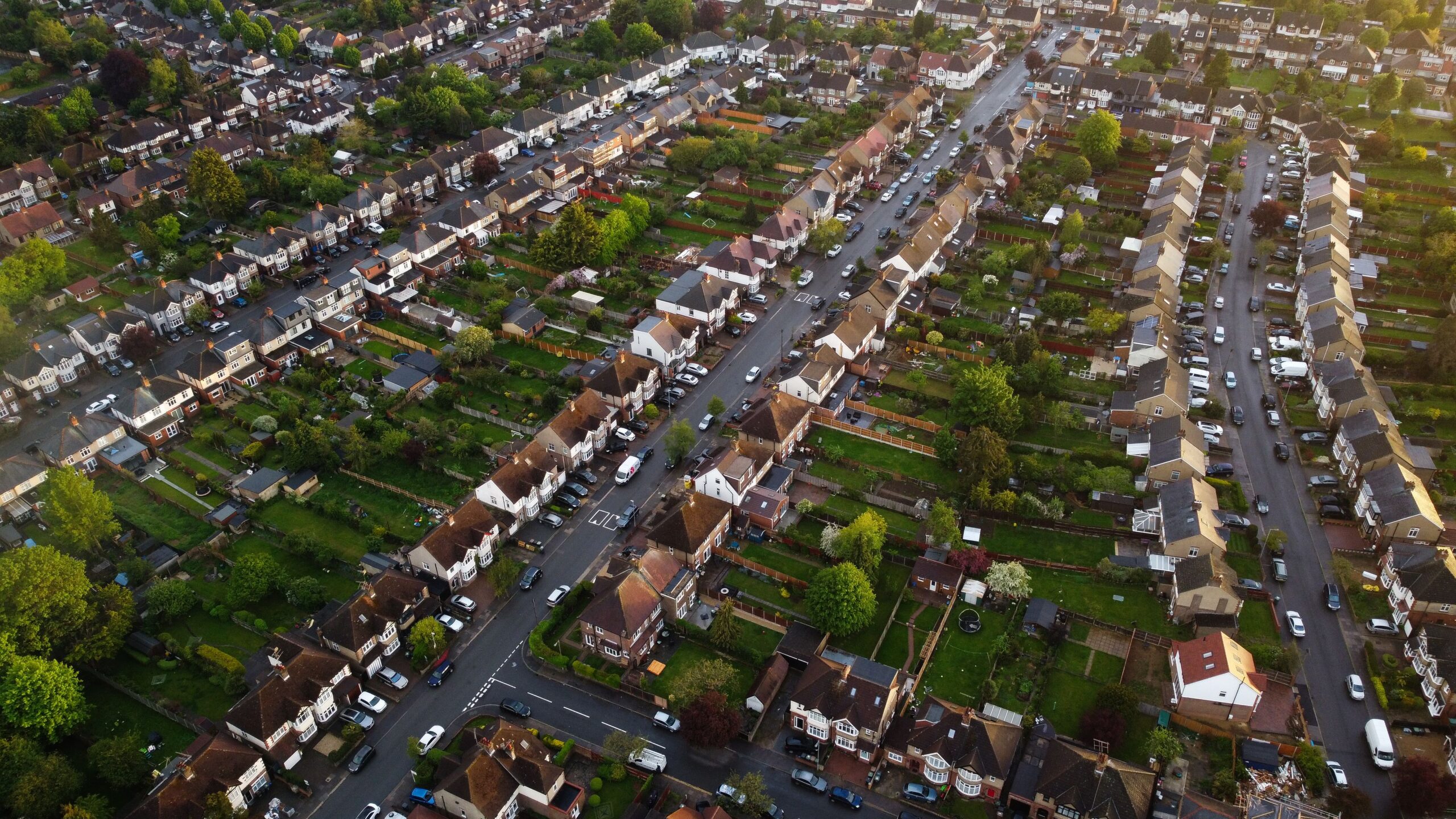 Aerial view of a residential neighbourhood with rows of houses, tree-lined streets and private back gardens.